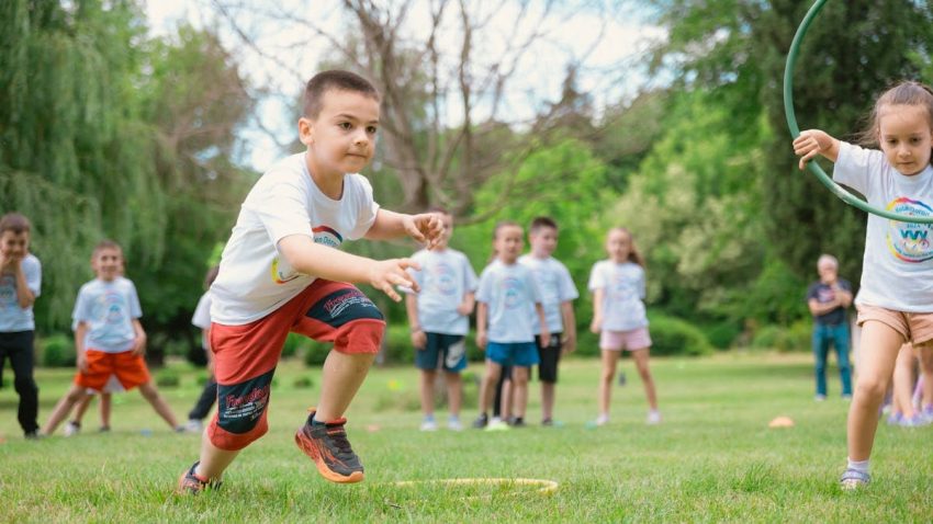 A group of children actively playing with hula hoops on a bright summer day in the park.